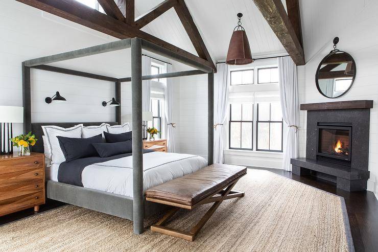 Cottage bedroom with a truss ceiling black granite corner fireplace with a wood mantel, shiplap wall trim, and a round black mirror white wood plank ceiling accented with dark stained wood truss trim