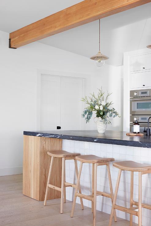 kitchen island with wood and black marble and white tiles faux wood beam