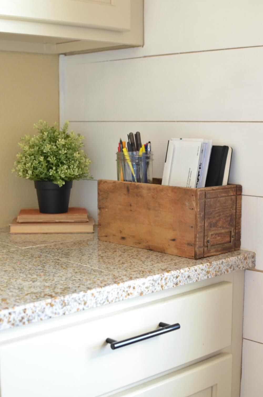 wooden vintage mail organizer on granite countertop with greenery in background