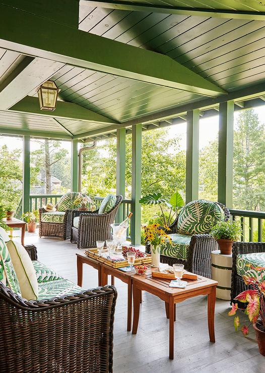 covered porch greek plank vaulted ceiling furnished with teak accent tables placed side-by-side between a dark brown wicker sofa with green cushions facing two matching dark brown wicker chairs