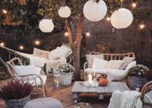 paper lanterns hanging in tree with outdoor seating white couches pumpkings