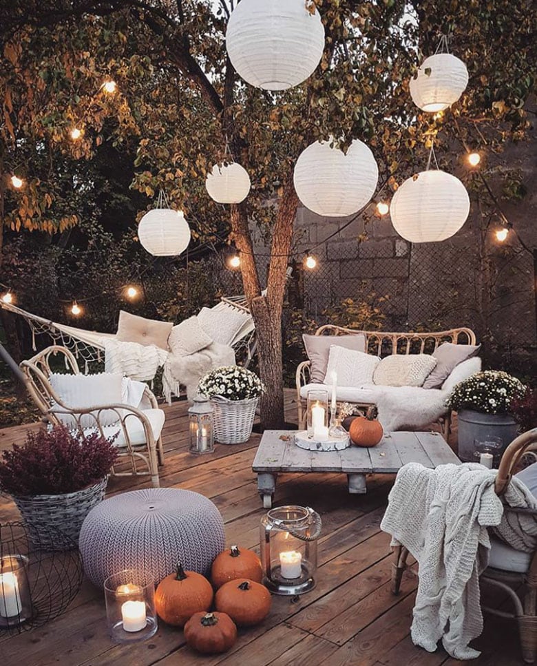 paper lanterns hanging in tree with outdoor seating white couches pumpkings