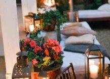 lit patio lanterns surrounded by flowers and pillows