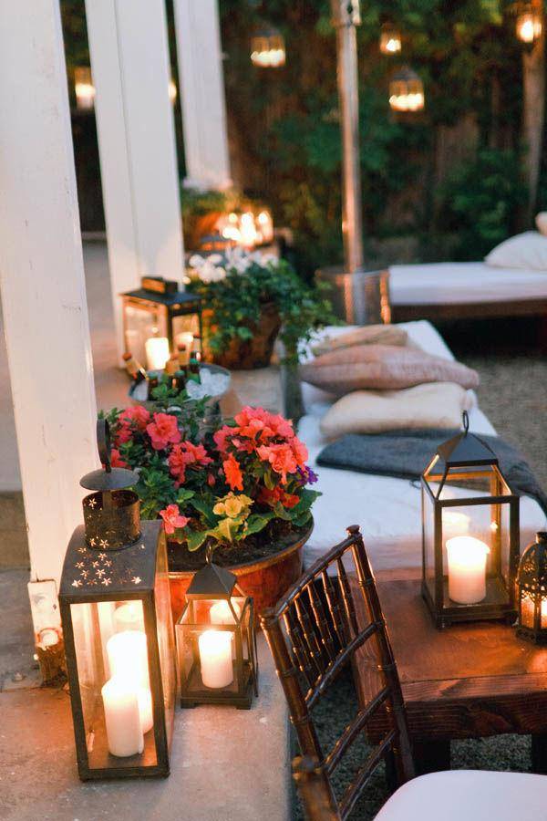 lit patio lanterns surrounded by flowers and pillows