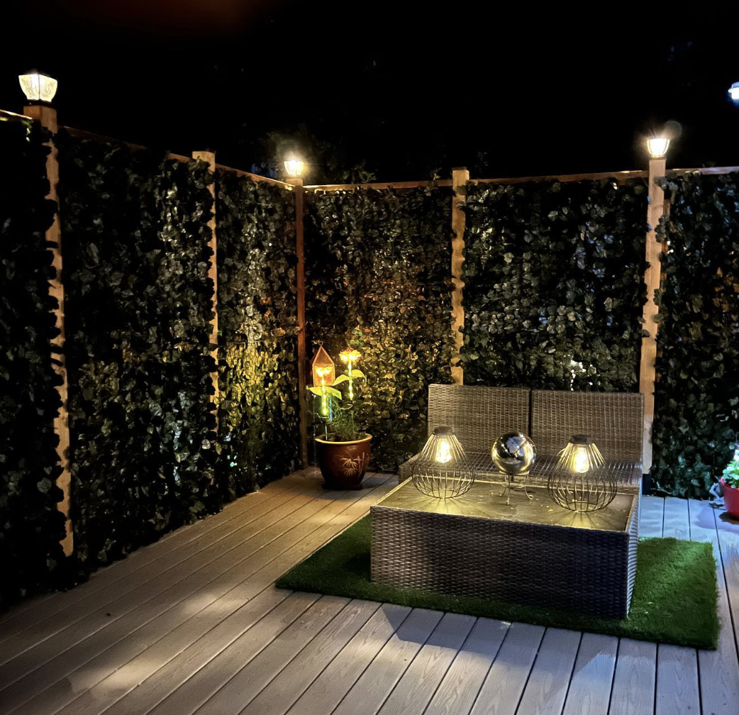 patio lanterns on top of leaf covered privacy walls backyard table lit up at night