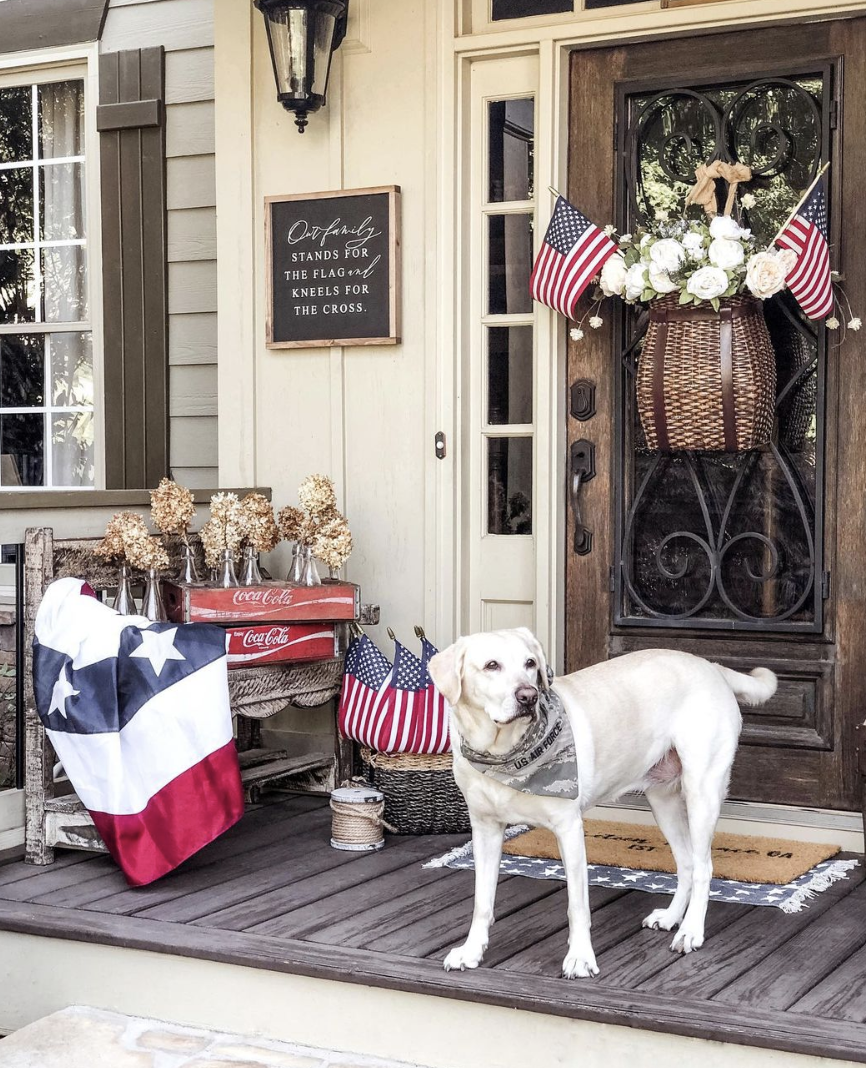 patriotic theme front porch with american flags and dog white lab with bandana on basket door decor with flags and flowers