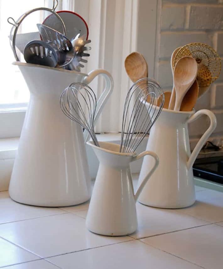 white pitchers with wooden spoons on kitchen counter