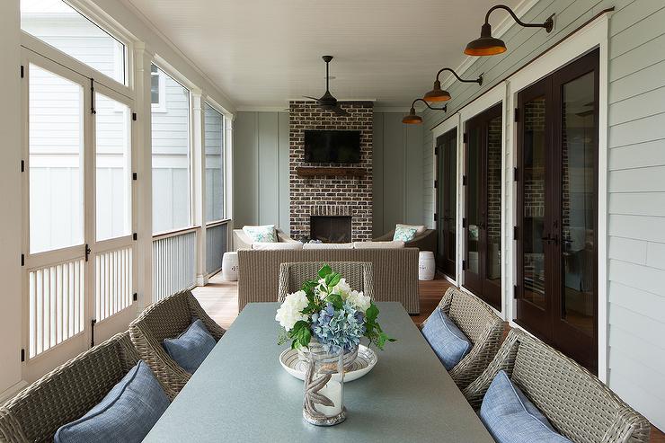 Enclosed back porch in a cottage home featuring a brick fireplace with a wood mantle and tv mounted overhead