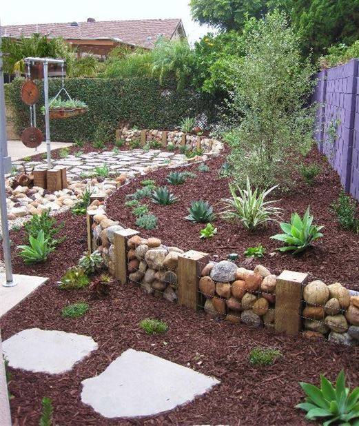 garden with rock retaining wall in wire mesh mulch and stones