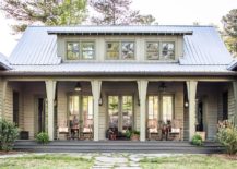 Green country cabin porch looks cozy and inviting with rocking chairs placed in front of a row of French doors.