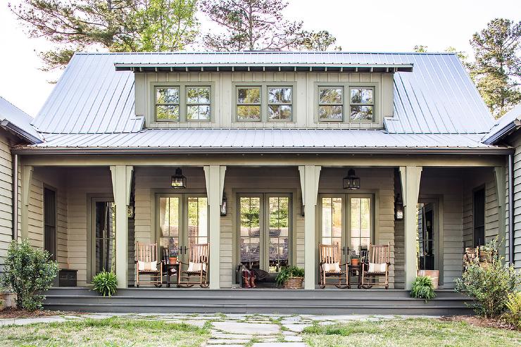 Green country cabin porch looks cozy and inviting with rocking chairs placed in front of a row of French doors.