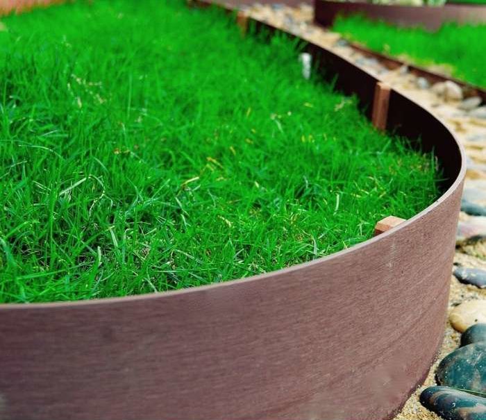 rolled plastic hardwood look edging around grass close up