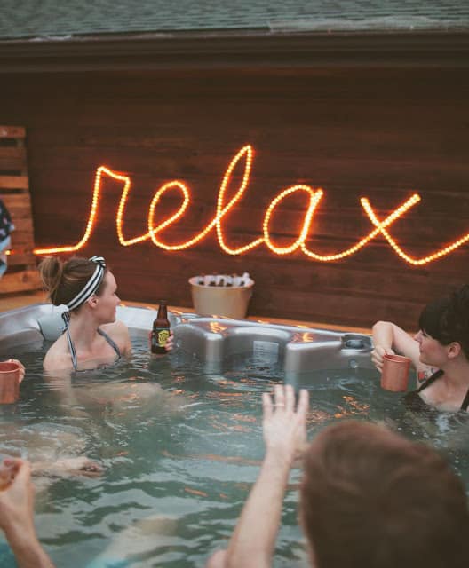 rope light relax outdoor sign lit up people in hot tub drinking