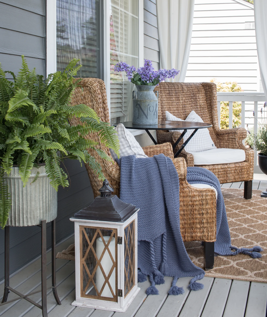 wicker armchairs on front porch with blue blanket throw metal tins flowers lanterns