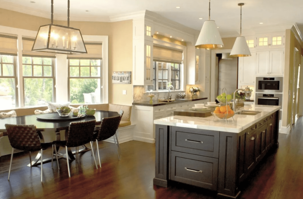 large kitchen with brown island table breakfast nook white pendants white cabinetry