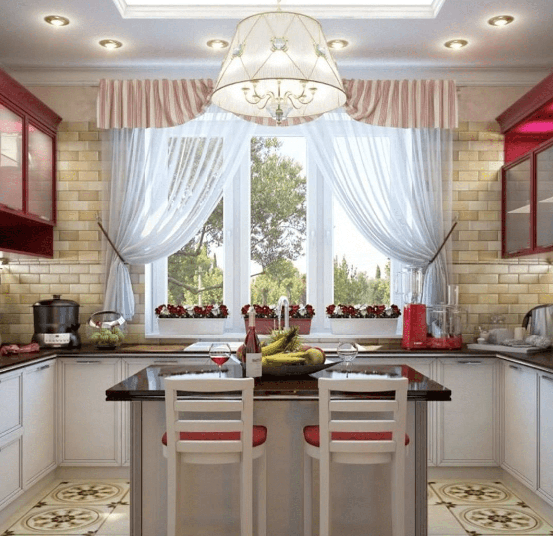 Large open kitchen with island in center white cabinetry red stools flowers in window sheer curtains with valance and white chandelier