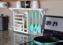 white wood spice rack and utensil holder on kitchen backsplash next to stove