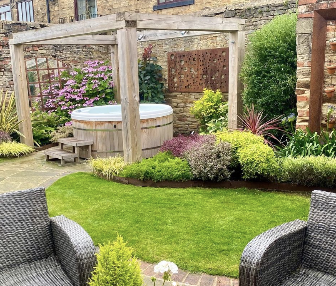 wide shot of garden with hot tub and open pergola grass green shrubs