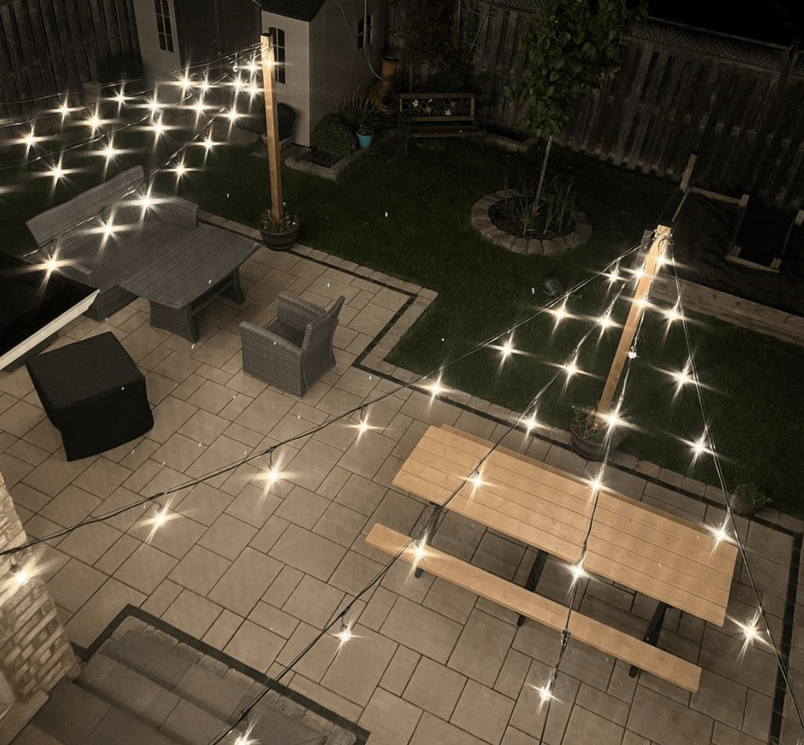view from up top of string lights strung across patio picnic table concrete shining at night