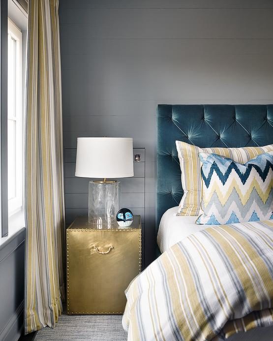 yellow and teal bedroom with velvet tufted headboard striped bedding and gold nightstand