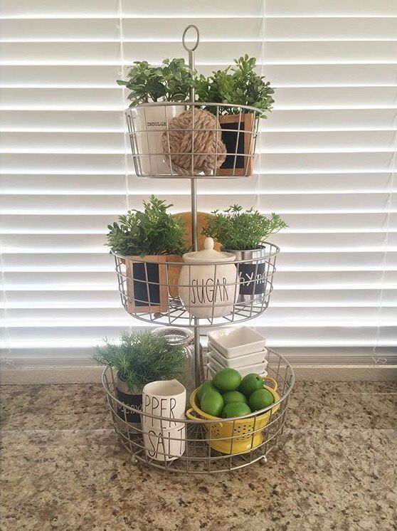 three tiered wire baskets on kitchen counter with greenery