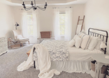 white fluffy blankets on black iron farmhouse bed in white large master bedroom with black chandelier