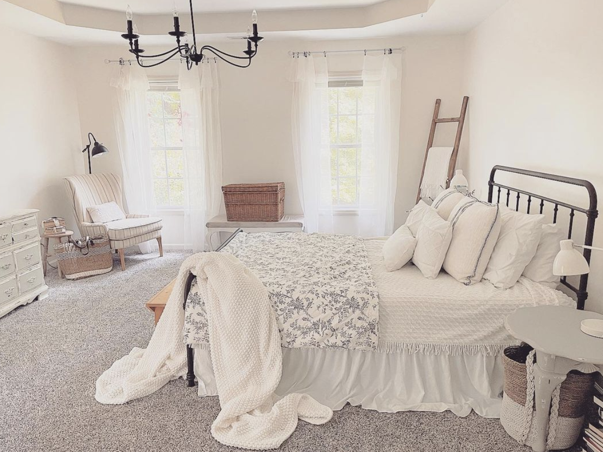 white fluffy blankets on black iron farmhouse bed in white large master bedroom with black chandelier