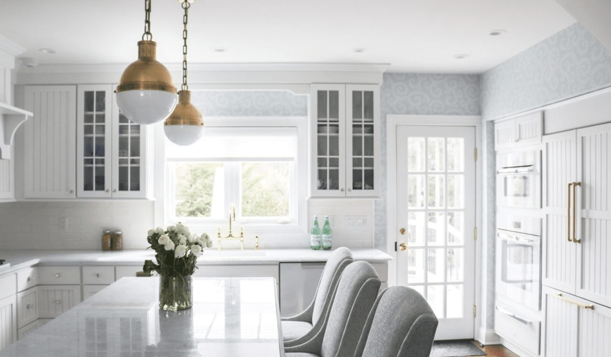 white large kitchen with gold hanging pendants glass cabinets and white door leading to outside