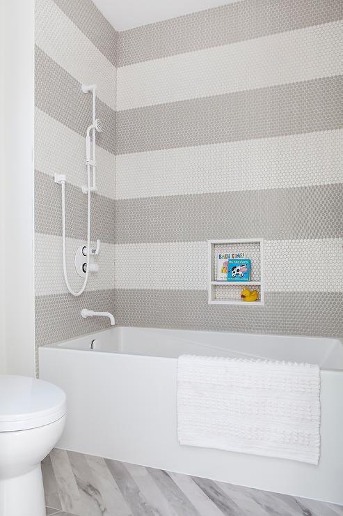White and gray penny shower tiles in a stripe pattern design in a bathtub white shower kit
