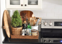 woven flat storage box on black kitchen counter next to stove with utensils and kitchen items