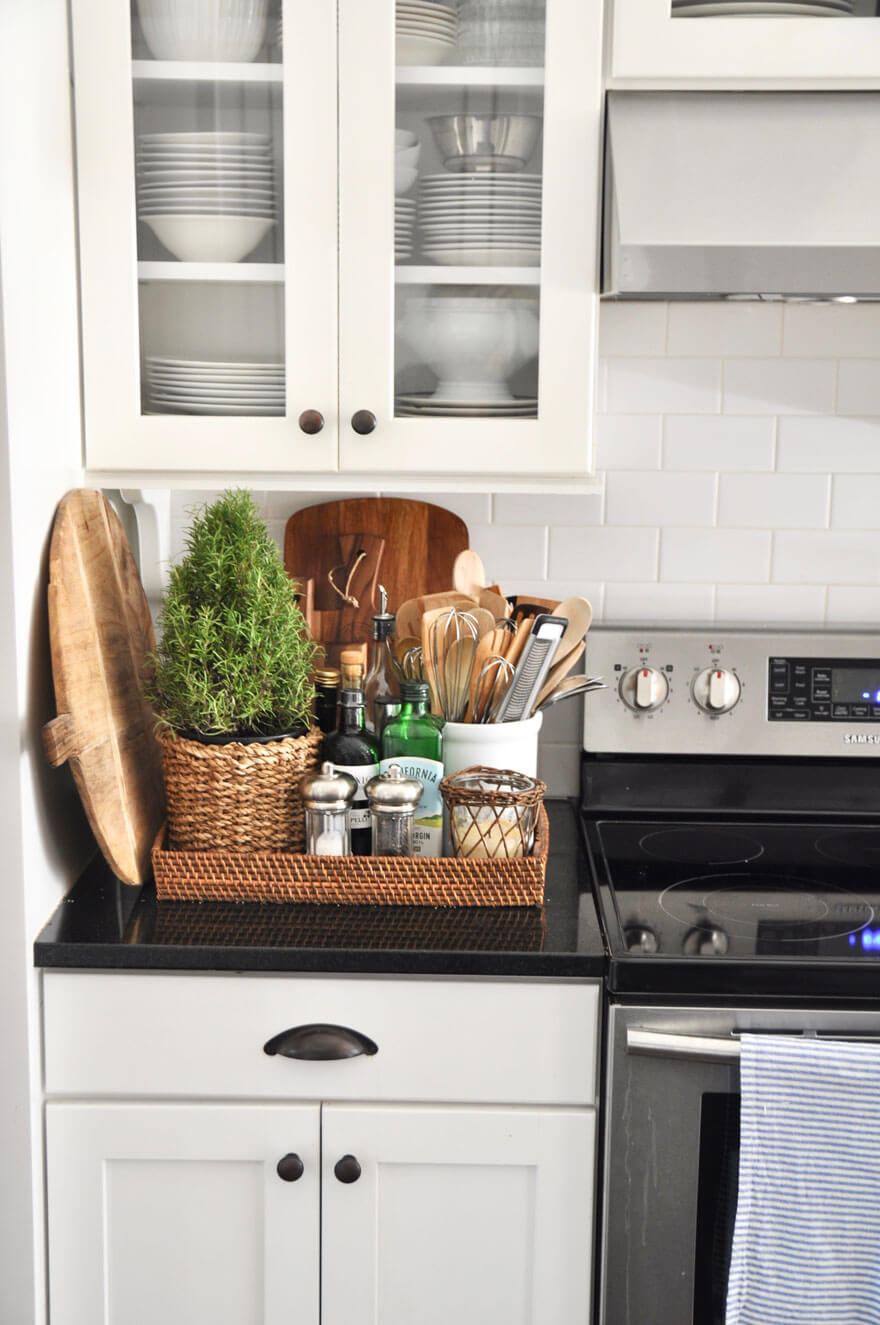 woven flat storage box on black kitchen counter next to stove with utensils and kitchen items