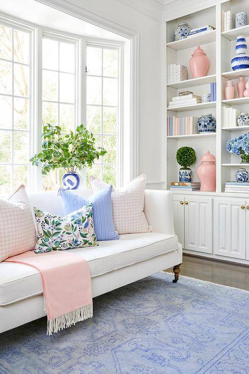 ruang tamu dengan rak buku dalam warna pink dan biru pastel