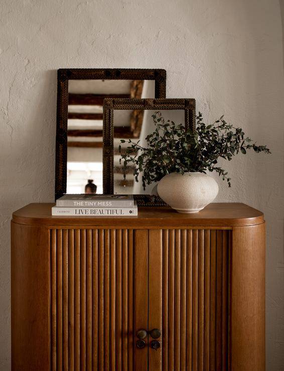 Antique mirrors sit on a vintage curved entry cabinet.