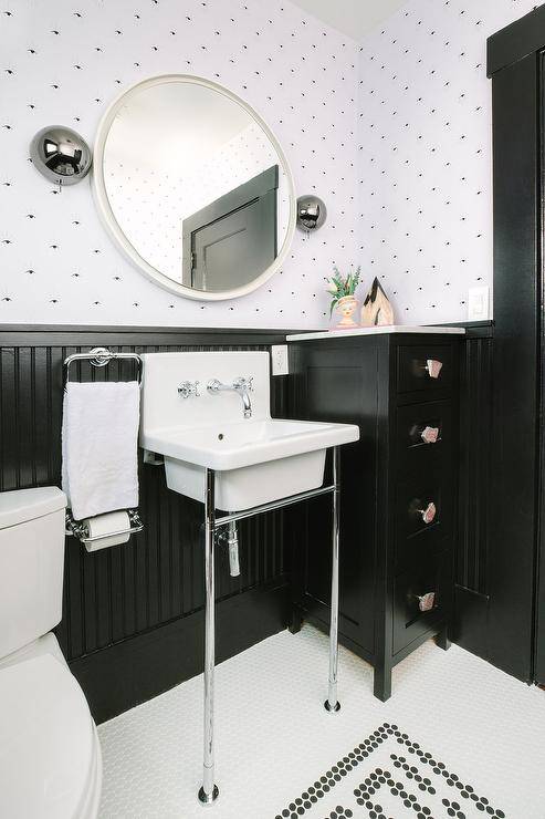 black vanity half bathroom board and batten wall dotted wallpaper round white mirror