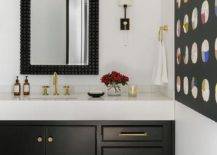 Contemporary bathroom features a black bath vanity with brass gooseneck faucet under a black penny tiled mirror and light gray and black mosaic tiles.