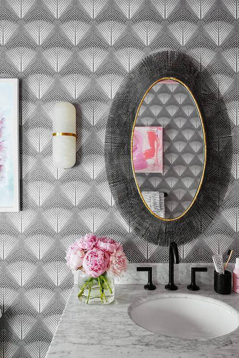 black eclectic mirror hanging on geometric black wallpaper in bathroom sink black faucet pink peonies