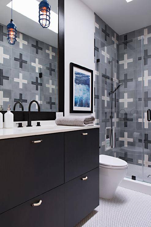 Contemporary bathroom features a blue cage pendant over a black and white sink vanity with a matte black gooseneck faucet, a black framed vanity mirror, black and gray shower tiles and white hexagon floor tiles.