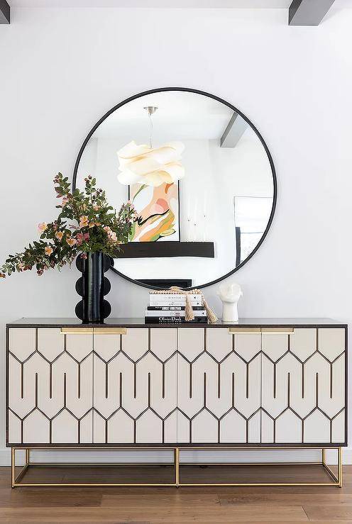 black round mirror over console table in white hallway