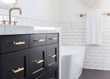 Black hexagon floor tiles in a transitional bathroom designed with a black shaker washstand, brass pulls and a thick marble countertop.