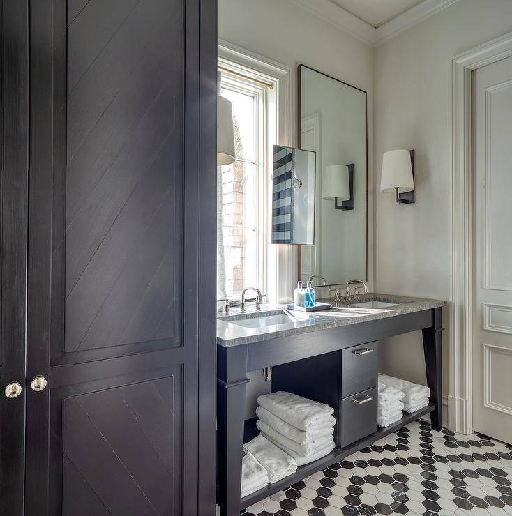 Bathroom features a black dual washstand with black marble countertop on a black and white marble hexagon floor and black chevron cabinet doors.