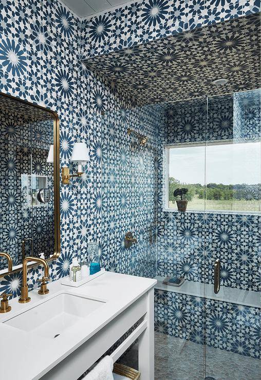 blue mosaic tiles floor to ceiling walk in shower with frameless glass doors gold faucet white counter sink gold mirror wall sconce