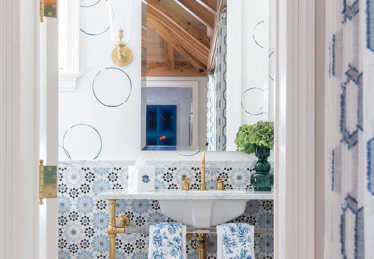 bold tile in half bathroom with gold faucet sink circle design on wall with gold sconce