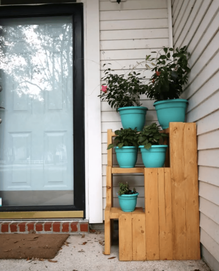 wood handmade diy corner plant stand with blue pots in front of front door
