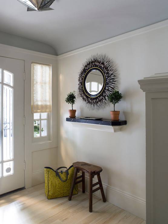 black eclectic mirror in entryway with wood bench