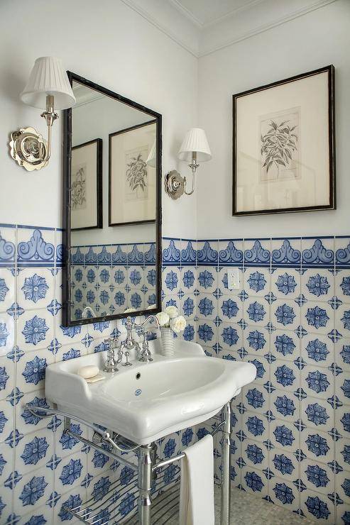 fancy tile in bathroom with pedestal sink black frame mirror and white wall sconces