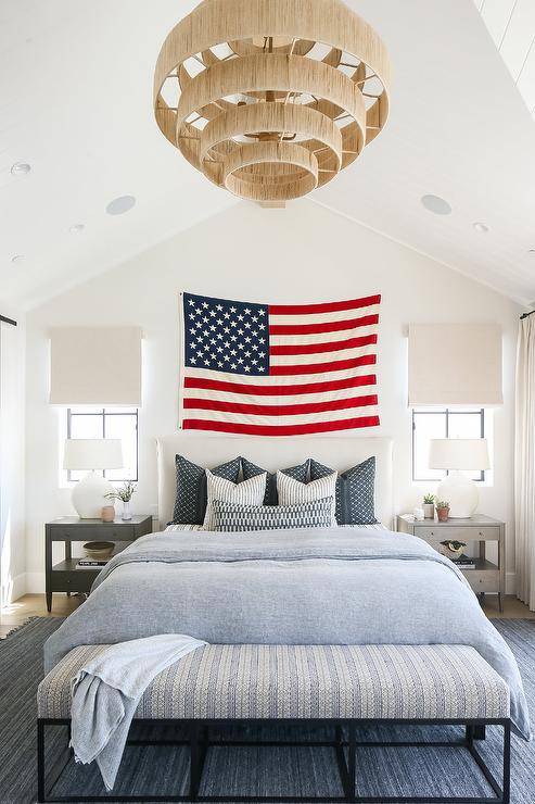 american flag hanging over bed light blue bedding white wall bedroom large chandelier