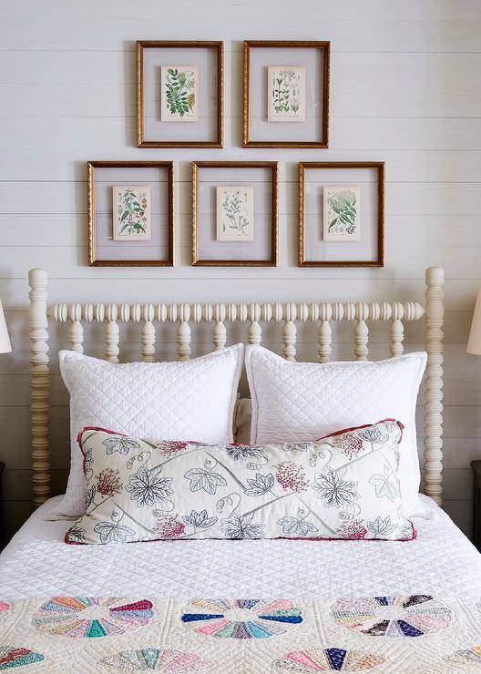 gold framed botanical prints hanging in a gallery wall above a white spindal bed