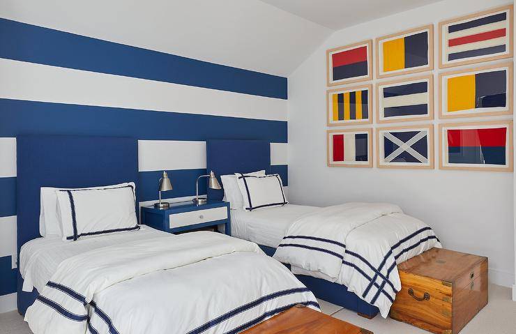 nautical decorated boys bedroom with framed flags striped blue and white accent wall