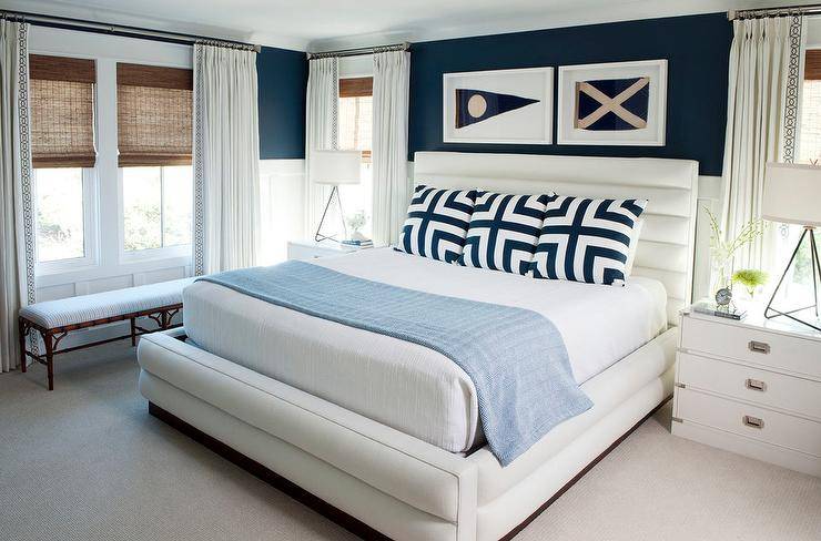 framed nautical flags hanging over bed white and undecorous sheets cottage style bedroom