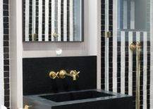 Bathroom features a black marble floating sink vanity with an antique brass cross handle faucet under a tall black box frame mirror.
